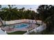 An aerial view of the fenced-in pool area with lounge chairs, dining table, artificial grass, and pavers at 501 Key Royale Dr, Holmes Beach, FL 34217