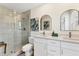Modern bathroom with a glass-enclosed shower and double vanity with trendy, arched mirrors at 501 Key Royale Dr, Holmes Beach, FL 34217