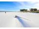 Expansive white sandy beach with a log washed ashore, perfect for leisurely walks and enjoying the calm ocean breeze at 501 Key Royale Dr, Holmes Beach, FL 34217