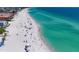 Aerial view of a beach with clear water, light sand, and rows of umbrellas with scattered beachgoers at 501 Key Royale Dr, Holmes Beach, FL 34217