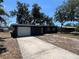 Charming single-story home showcasing a dark gray exterior, a two-car garage and mature trees in the front yard at 5030 Lahaina Dr, Sarasota, FL 34232