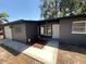 Charming single-story home showcasing a dark gray exterior, a two-car garage and mature trees in the front yard at 5030 Lahaina Dr, Sarasota, FL 34232