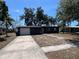 Charming single-story home showcasing a dark gray exterior, a two-car garage and mature trees in the front yard at 5030 Lahaina Dr, Sarasota, FL 34232