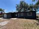 Charming single-story home showcasing a dark gray exterior, a two-car garage and mature trees in the front yard at 5030 Lahaina Dr, Sarasota, FL 34232
