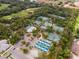 Aerial view of well-maintained tennis courts, swimming pool, and clubhouse surrounded by lush greenery at 5336 Huntingwood Ct # 24, Sarasota, FL 34235