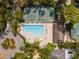 Aerial view of a community pool, tennis court, and surrounding trees, showcasing recreational amenities at 5336 Huntingwood Ct # 24, Sarasota, FL 34235