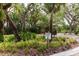 Sign pointing to the butterfly garden with lush greenery and mature trees providing shade at 5336 Huntingwood Ct # 24, Sarasota, FL 34235