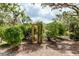 Wooden archway entrance to garden surrounded by mature plants, bushes and crushed gravel path at 5336 Huntingwood Ct # 24, Sarasota, FL 34235