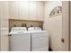 A laundry room features white cabinets above and side-by-side washer and dryer units at 5336 Huntingwood Ct # 24, Sarasota, FL 34235
