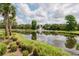Picturesque pond with a water fountain, surrounded by palm trees, and green landscaping at 5336 Huntingwood Ct # 24, Sarasota, FL 34235