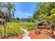 Picturesque backyard with lush landscaping, a tranquil pond, and a stone path winding through the greenery at 6304 Pelican Dr, Bradenton, FL 34210