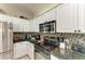 Galley style kitchen featuring granite countertops, tiled backsplash, and stainless steel appliances at 6546 Blue Grosbeak Cir, Lakewood Ranch, FL 34202