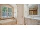 Bathroom with tile floors, white vanity, soaker tub and arched window at 6931 Brier Creek Ct, Lakewood Ranch, FL 34202