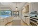 Well-lit kitchen with white cabinets, stainless steel appliances, island with quartz countertops, and pool view access at 6931 Brier Creek Ct, Lakewood Ranch, FL 34202
