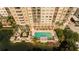 Aerial view of a building and its pool area with lush landscaping, water views, and outdoor seating at 750 N Tamiami Trl # 208, Sarasota, FL 34236
