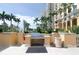 Community grill area with a built-in barbecue, palm trees, and a fountain in the background at 750 N Tamiami Trl # 208, Sarasota, FL 34236
