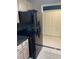 Kitchen features a black refrigerator, light wood cabinets, and tile floors at 750 N Tamiami Trl # 208, Sarasota, FL 34236
