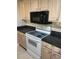 Well-equipped kitchen with modern appliances, light wood cabinets, and tile backsplash at 750 N Tamiami Trl # 208, Sarasota, FL 34236