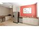 Kitchenette with stainless steel appliances, granite countertops, and a red accent wall with artwork at 750 N Tamiami Trl # 208, Sarasota, FL 34236