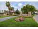 Community entrance sign surrounded by lush landscaping and colorful flower beds at 9774 Highland Park Pl, Palmetto, FL 34221