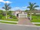 Charming single-story home featuring lush landscaping, a brick driveway, and two palm trees in the front yard at 9774 Highland Park Pl, Palmetto, FL 34221