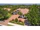 Aerial view of a beautifully landscaped Mediterranean-style home with a tile roof and circular paver driveway at 11447 Savannah Lakes Dr, Parrish, FL 34219
