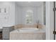 Bright bathroom features a soaking tub with tile surround and a window with plantation shutters at 11447 Savannah Lakes Dr, Parrish, FL 34219