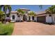 Elegant single-story home with a tile roof, brick driveway, and lush tropical landscaping at 11447 Savannah Lakes Dr, Parrish, FL 34219