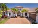 Stunning Mediterranean-style home with a tile roof, arched entryway, and a paver driveway surrounded by lush landscaping at 11447 Savannah Lakes Dr, Parrish, FL 34219
