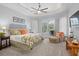 Comfortable main bedroom with ceiling fan, large windows, and sitting area with ottoman at 11447 Savannah Lakes Dr, Parrish, FL 34219