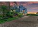 Beautiful waterfront home with a blue exterior, mature landscaping, and a paver driveway at 12 Tidy Island Blvd, Bradenton, FL 34210