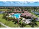 Aerial view of community clubhouse featuring a large pool, tennis courts, and ample parking at 12315 Canavese Ln, Venice, FL 34293