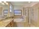 Bright bathroom with a granite countertop vanity, soaking tub, and a separate glass-enclosed shower at 12315 Canavese Ln, Venice, FL 34293