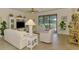 Comfortable living area with plush white furniture and view of screened lanai and backyard pond at 12315 Canavese Ln, Venice, FL 34293