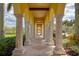 Arched walkway with stone pillars, manicured landscaping, and tiled floors at 12315 Canavese Ln, Venice, FL 34293