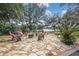 Spacious stone patio with fire pit and lush landscaping overlooking a serene lake at 127 Mill E Run, Bradenton, FL 34212