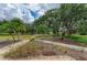 Landscaped backyard with a walking path, mature trees, and view of the pond at 127 Mill E Run, Bradenton, FL 34212