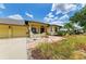 Charming yellow home featuring a red front door, well-manicured lawn, and a two-car garage at 127 Mill E Run, Bradenton, FL 34212