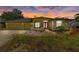Charming yellow home with a red front door, well-manicured lawn during sunset with two-car garage at 127 Mill E Run, Bradenton, FL 34212