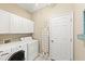 Functional laundry room with white appliances, cabinets, ironing board and natural lighting at 127 Mill E Run, Bradenton, FL 34212
