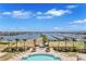 An aerial view of a waterfront property showcasing a pool, manicured lawn, and harbor with boats at 130 Riviera Dunes Way # 502, Palmetto, FL 34221