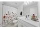 Cozy bathroom with a floral shower curtain, a white vanity, and modern fixtures at 15051 Ginetti St, Nokomis, FL 34275