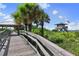 Wooden boardwalk leading to the beach, featuring a lifeguard tower and covered seating area amidst tropical foliage at 15051 Ginetti St, Nokomis, FL 34275