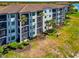 Beautiful condo building with tiled roof, screened in balconies, lush landscaping, and a glimpse of a lake at 16804 Vardon Ter # 205, Bradenton, FL 34211