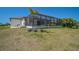Exterior view of home with a large screened-in pool area and spacious lawn at 260 Marker Rd, Rotonda West, FL 33947