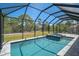 Screened-in pool and spa area surrounded by lush landscaping and clear blue skies at 260 Marker Rd, Rotonda West, FL 33947