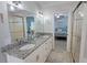 Stylish bathroom featuring double sinks, granite countertops, and tiled floors with a view into the bedroom at 3740 Gulf Of Mexico Dr # 116, Longboat Key, FL 34228