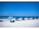 Relax on this white sandy beach with beach chairs and blue umbrellas under a bright blue sky at 4122 Central Sarasota Pkwy # 1923, Sarasota, FL 34238