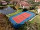 Aerial view of a vibrant tennis court adjacent to a tranquil pond, surrounded by lush greenery at 4122 Central Sarasota Pkwy # 1923, Sarasota, FL 34238
