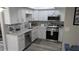 This is a pristine kitchen featuring white cabinets, stainless steel appliances, and laminate flooring at 4158 Tamiami Trl # V1, Port Charlotte, FL 33952